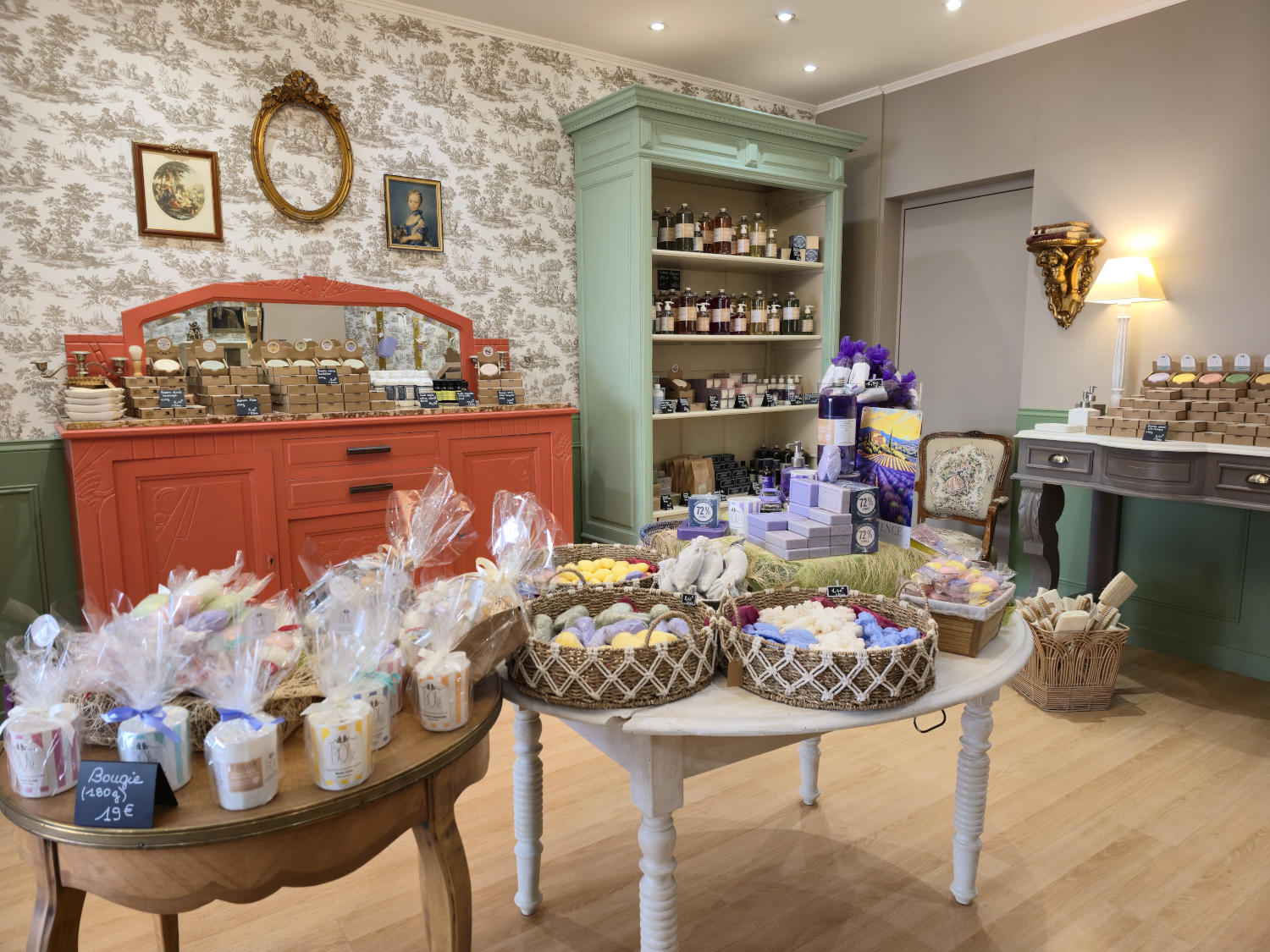 Innenansicht eines Ladens, der handgefertigte Produkte verkauft, mit Seifen, Kerzen und Kosmetika auf Tischen und Regalen.