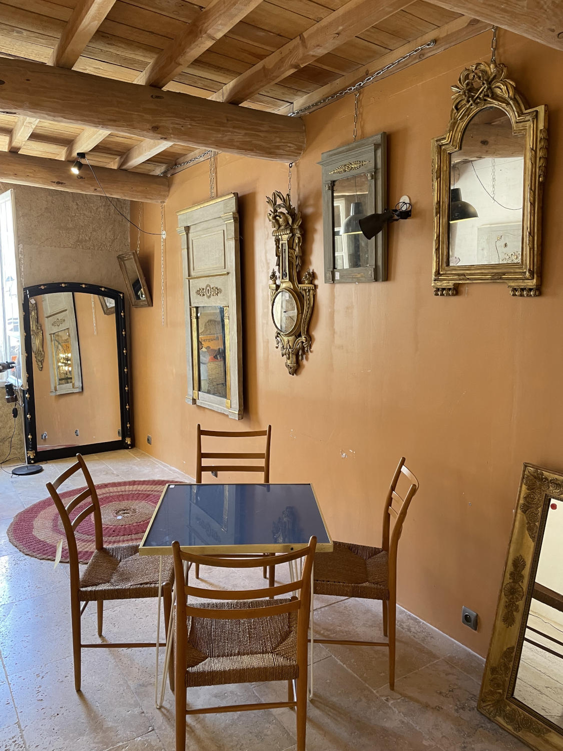 Warmes Wohnzimmer im Vintage-Stil mit unverputzten Steinwänden, Holzsesseln, Spiegelkollektion und sanfter Beleuchtung.