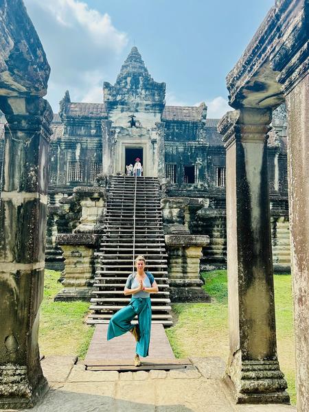 Eine Frau macht die Baumpose vor dem Angkor Wat Tempel.