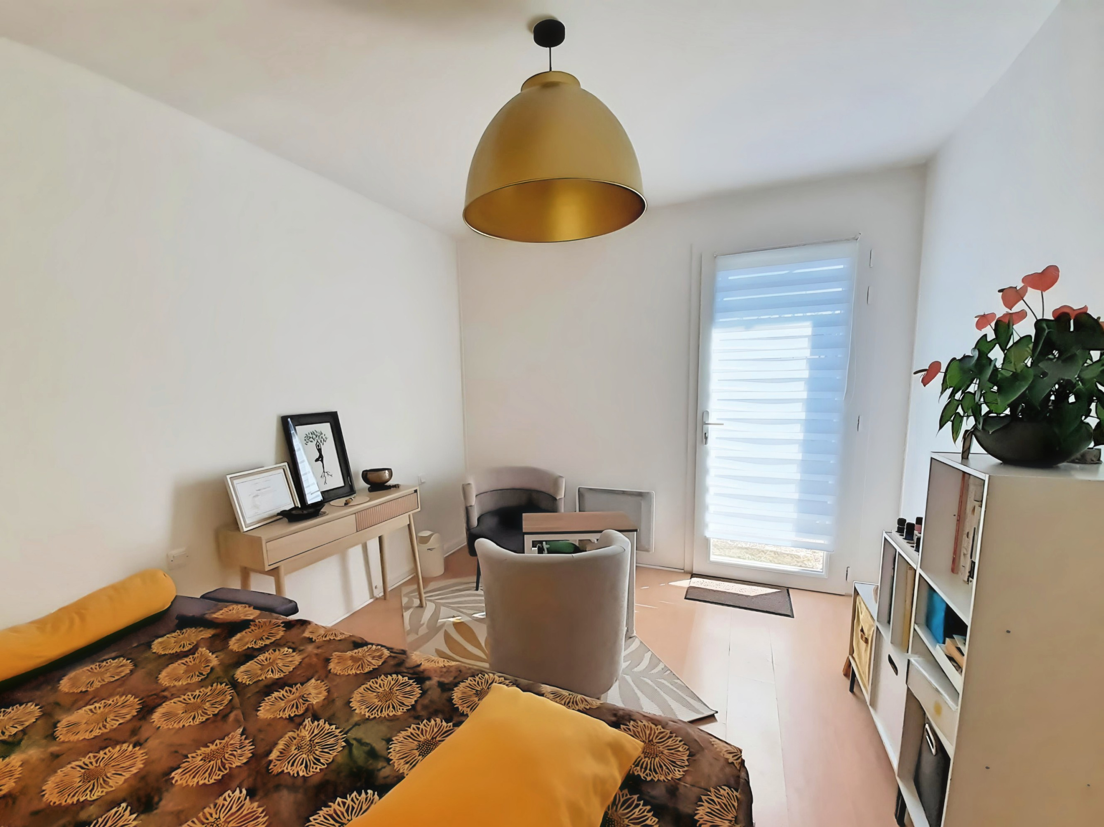 Helles, modernes Zimmer mit einem gelb gemusterten Sofa, Schreibtisch, Stühlen und einer Terrassentür nach draußen.