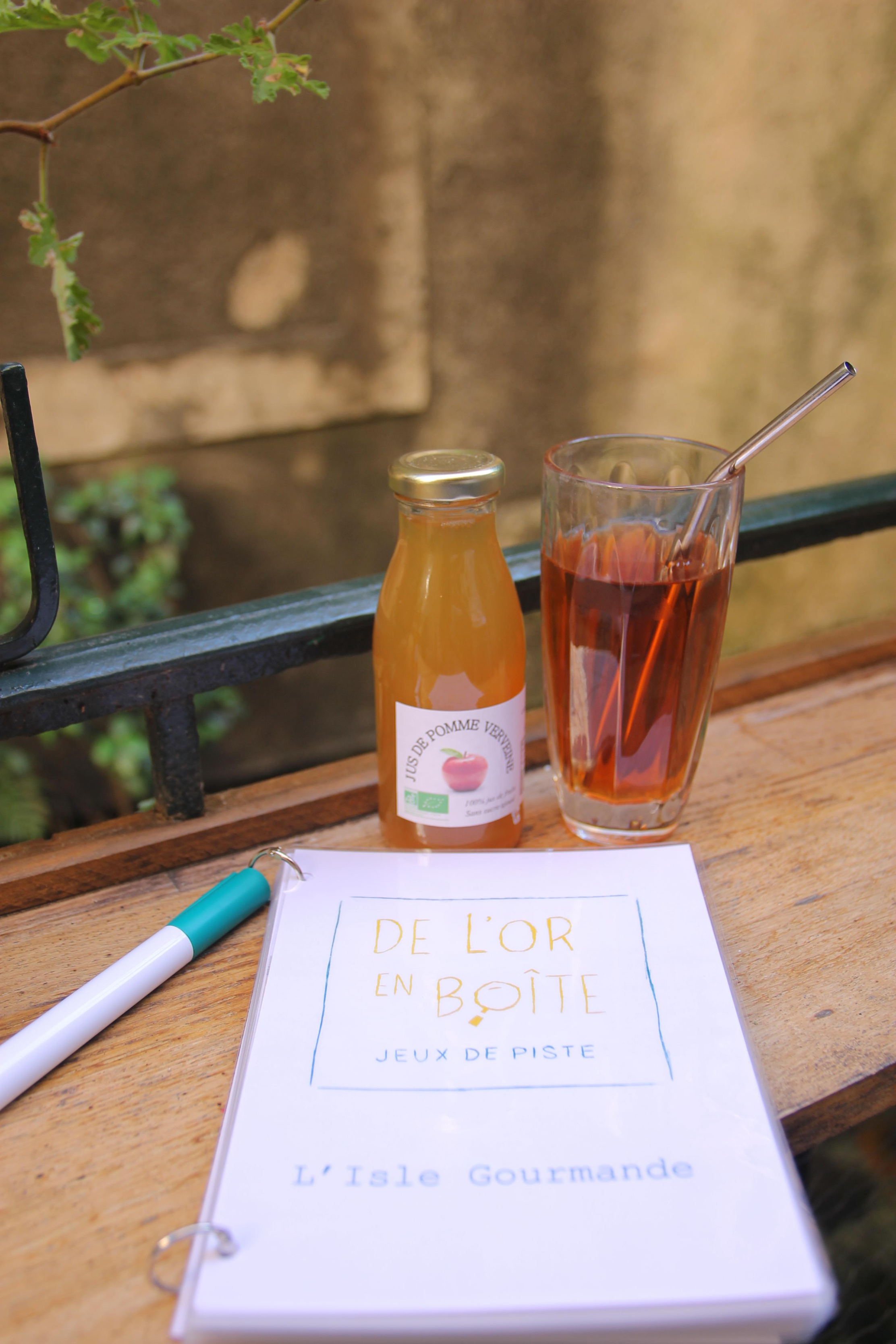 Eine Flasche Apfelsaft und ein Glas Eistee auf einem Holztisch neben