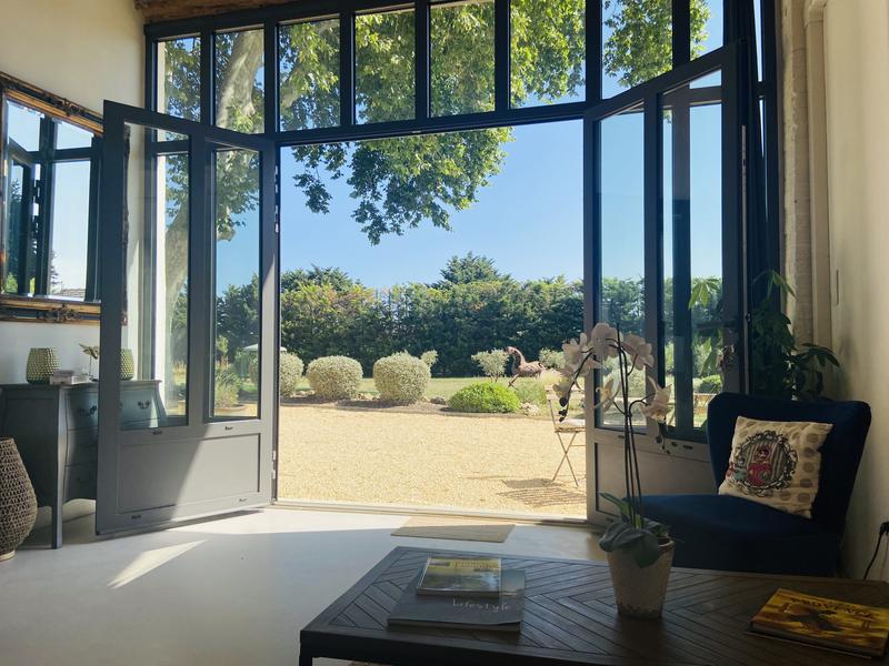 Helles Wohnzimmer mit Zugang zu einem grünen Garten unter einer großen Platane.