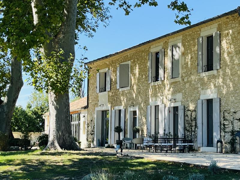 Provenzalisches Steinhaus mit grauen Fensterläden, schattiger Terrasse und großem Garten.