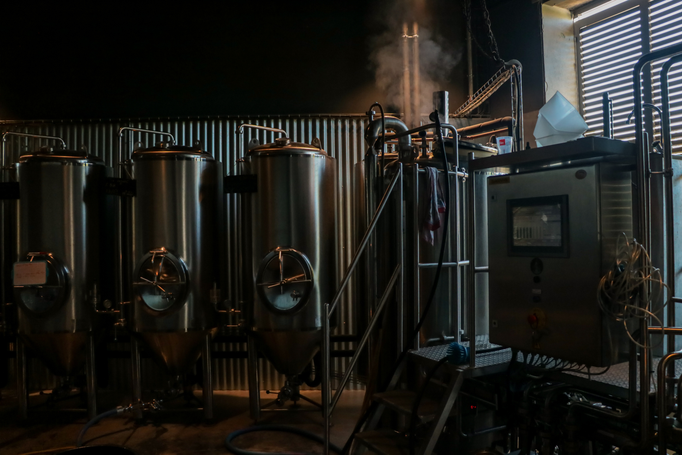 Edelstahltanks und Dampfmaschine in einer Handwerksbrauerei.