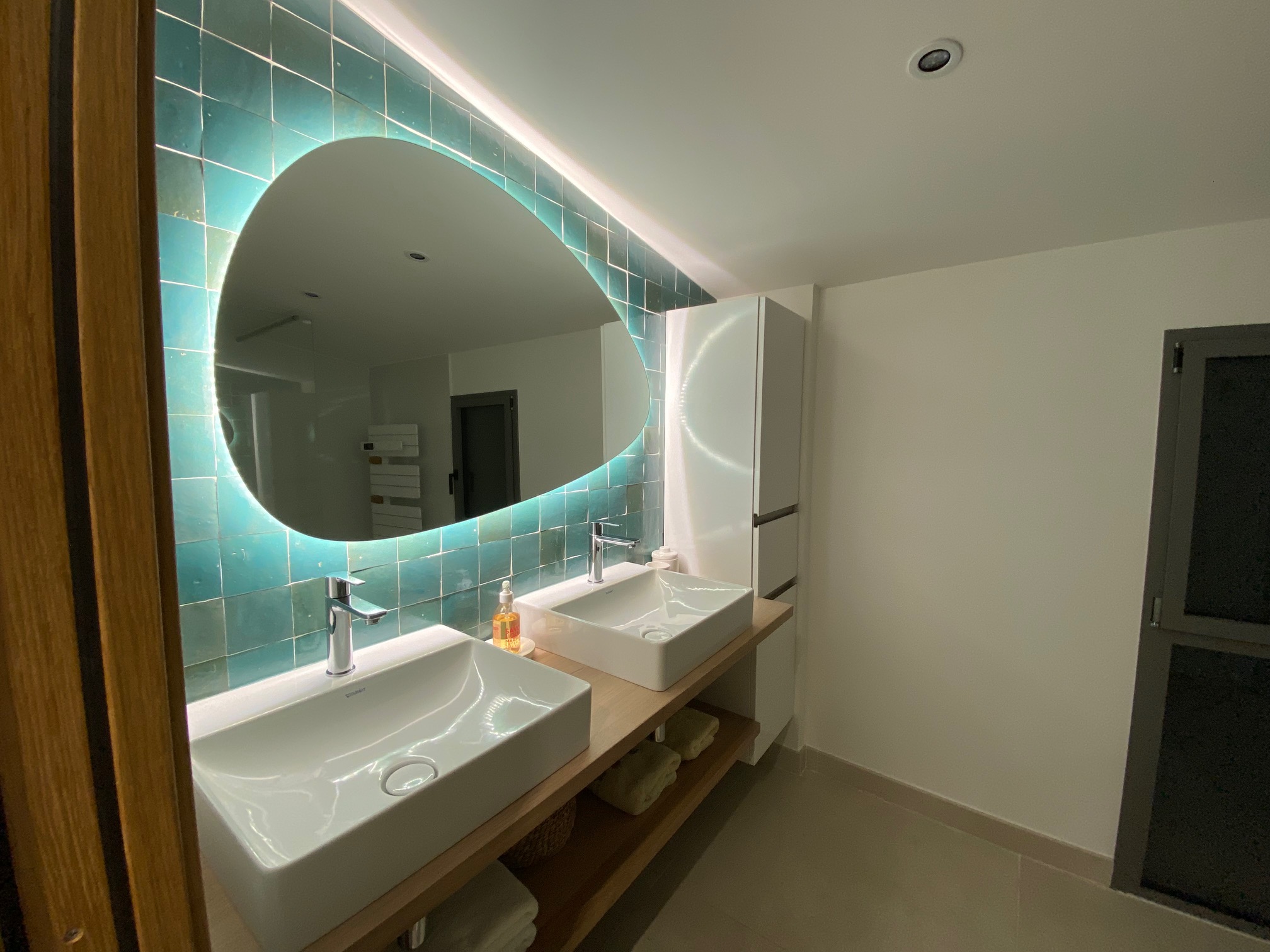 Badezimmer mit Doppelwaschbecken und ovalem Spiegel 