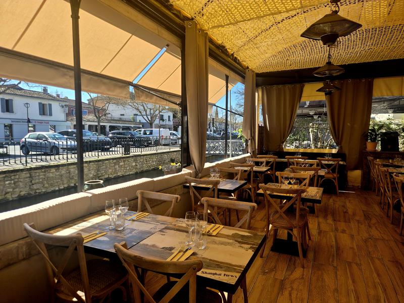 Eine lichtdurchflutete Restaurantterrasse mit Holztischen und Blick auf das Dock. Die Atmosphäre ist warm und ideal für eine Mahlzeit im Freien.