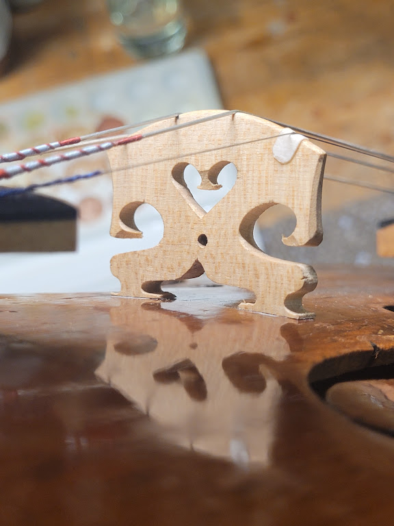 Nahaufnahme auf einer Geigenbrücke, die in Lucas Gauthier-Lurtys Werkstatt frisch von Hand geschnitten und angepasst wurde. Dieses unverzichtbare Stück des Instruments, das mit Präzision aus Ahorn geformt wurde, veranschaulicht die akribische Arbeit des Geigenbauers zur Optimierung der Schwingungsübertragung und der Klangqualität der Geige.