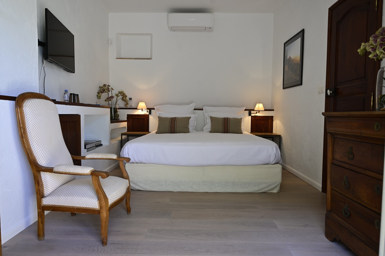 Dieses helle Zimmer verbindet Schlichtheit und provenzalischen Charme mit seinen antiken Holzmöbeln, natürlichen Farbtönen und raffiniertem Dekor. Das große Doppelbett, die warme Beleuchtung und die moderne Ausstattung schaffen eine komfortable und beruhigende Atmosphäre, ideal für einen ruhigen Aufenthalt im Herzen der Provence.