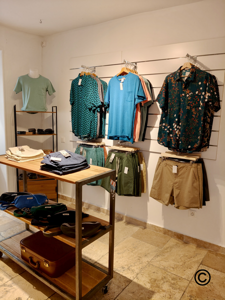 Dieser Bereich des Ladens ist der Herrenmode gewidmet und bietet eine Auswahl an Kleidung in lässigen und modernen Stilen. Bedruckte Hemden, farbenfrohe T-Shirts, Shorts und Accessoires werden in einem schlichten und eleganten Ambiente präsentiert, das Wert auf Materialien und Schnitte legt. Die Kollektion vereint Komfort, Qualität und Originalität in einem von Reise- und Sommertrends inspirierten Stil. 