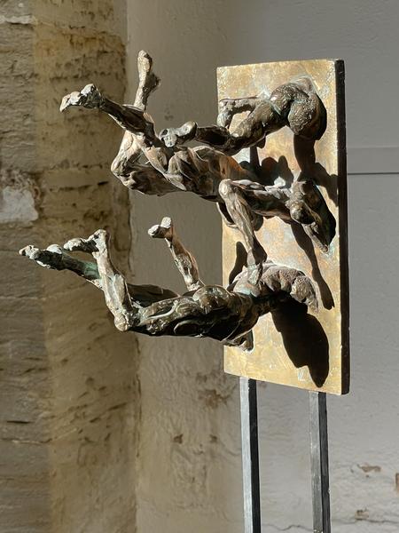 Dieses zweite Bild zeigt eine Bronzeskulptur, die aus zwei menschlichen Figuren besteht, die aus