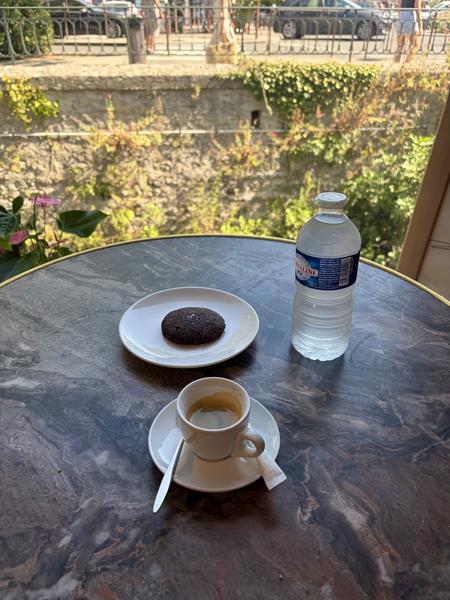 Kaffeepause in Orlie mit einem Espresso und einem Keks, installiert in der Nähe eines großen Erkerfensters mit Blick auf die Vegetation und die Kais von L